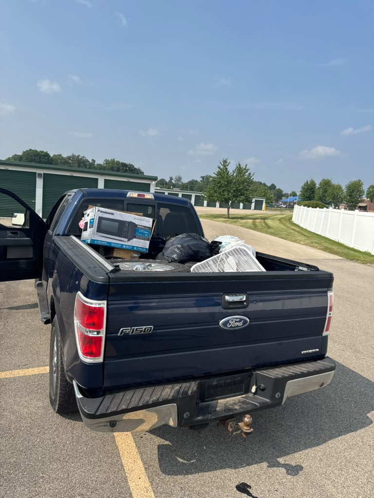 Our two-person crew in purple shirts carrying a dresser out of a Rockford garage